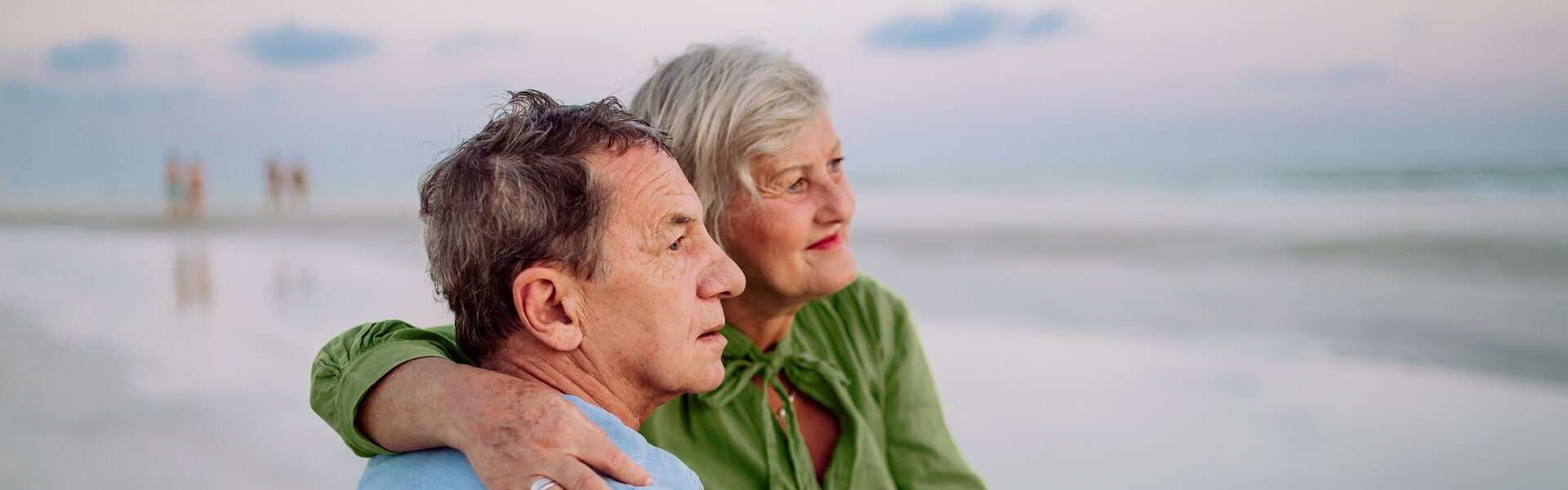 Woman sits with man in wheelchair on the beach 